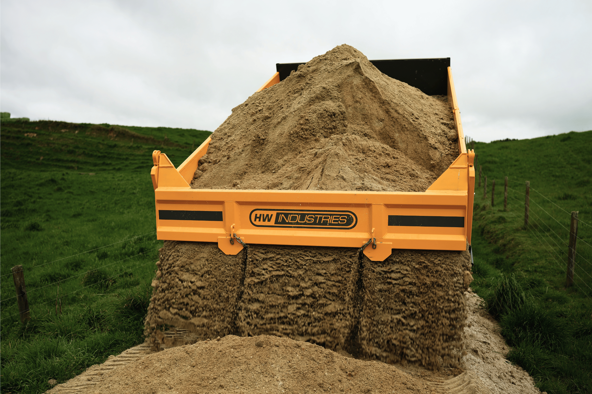Material flowing out of the rear of an HW Maxi tip trailer onto a farm track