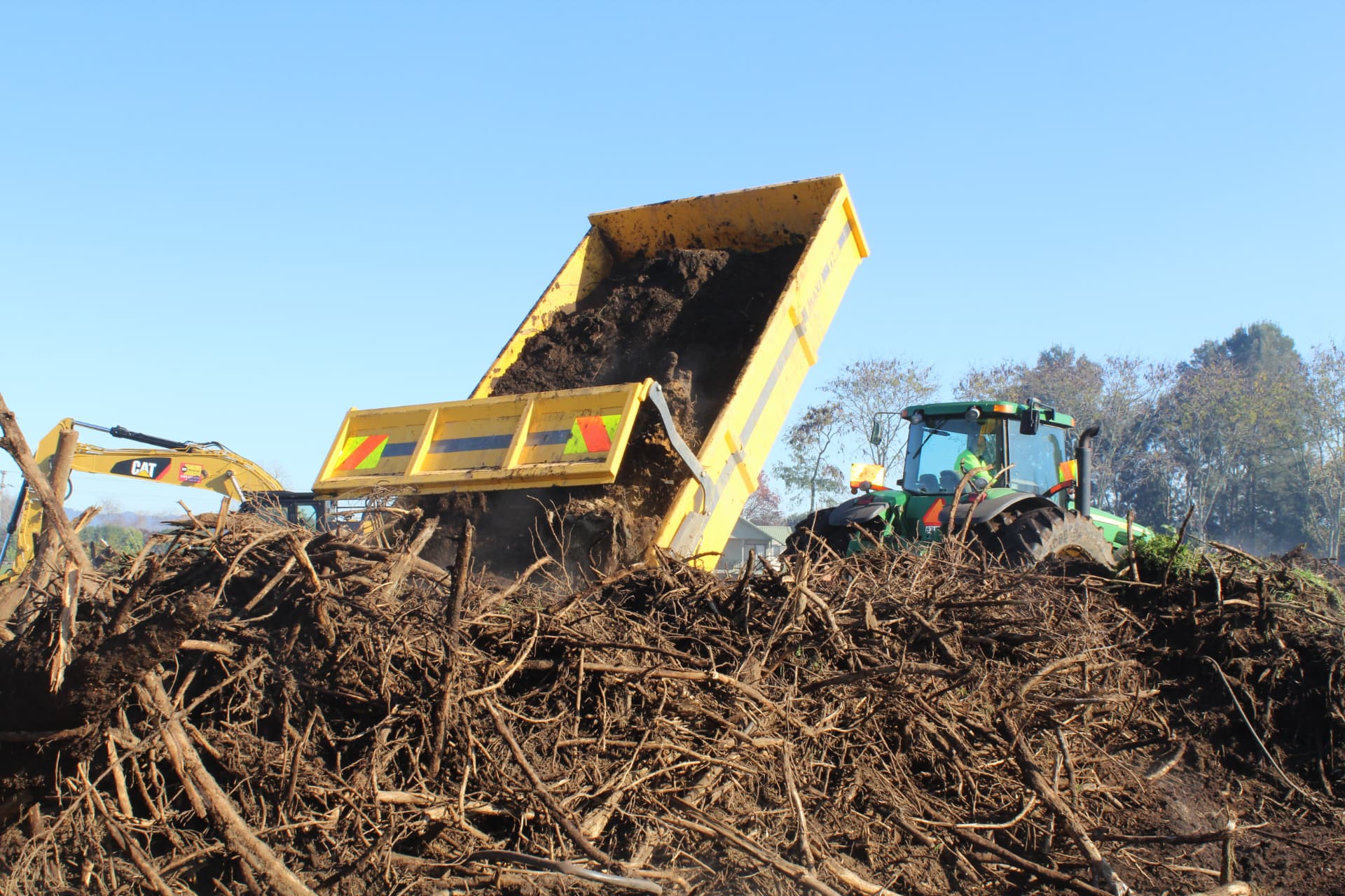 Maxi T140 tip trailer tipping soil and roots onto a pile of cleared vegetation