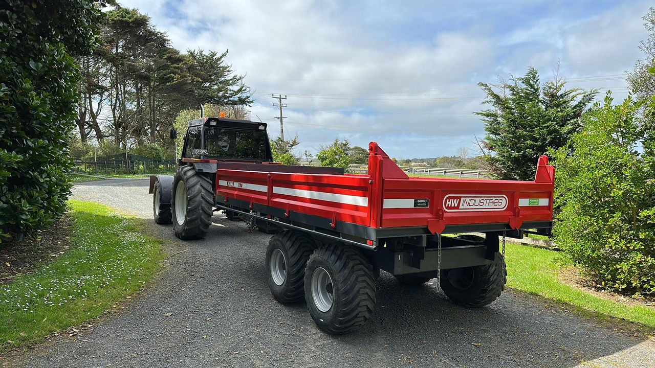Red Maxi T80 tip trailer behind a tractor on a farm driveway
