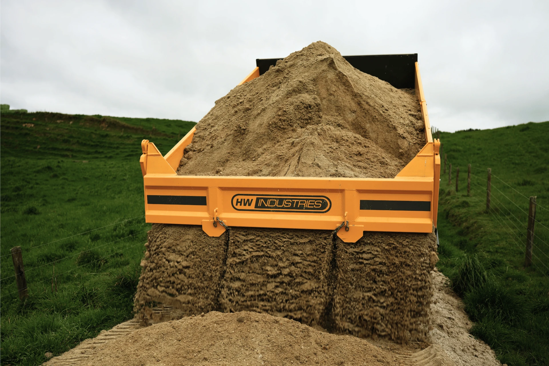 Material flowing evenly from the high-pivot tailgate of an HW tip trailer onto a farm laneway