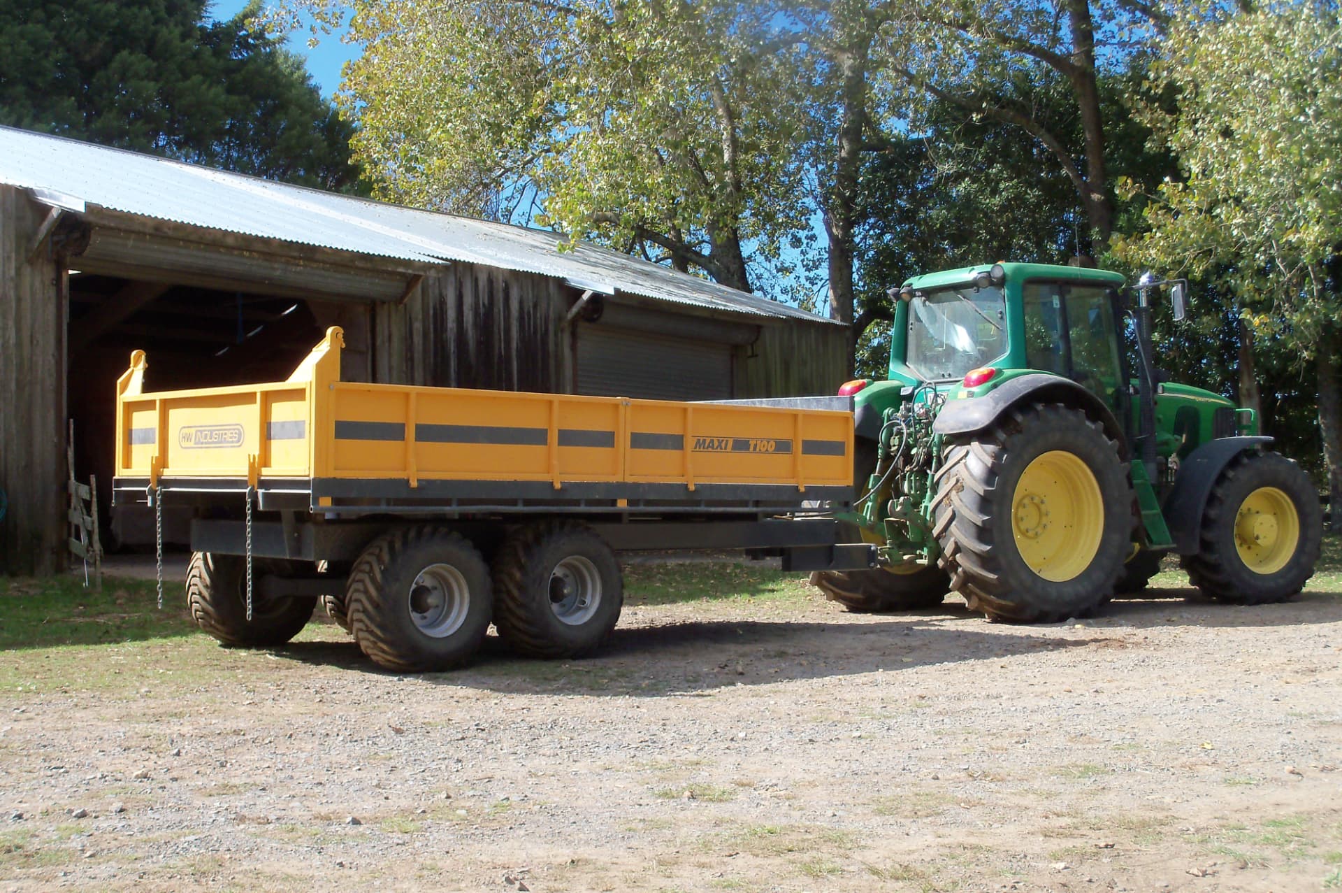 Maxi T100 tip trailer behind a John Deere tractor outside a farm shed